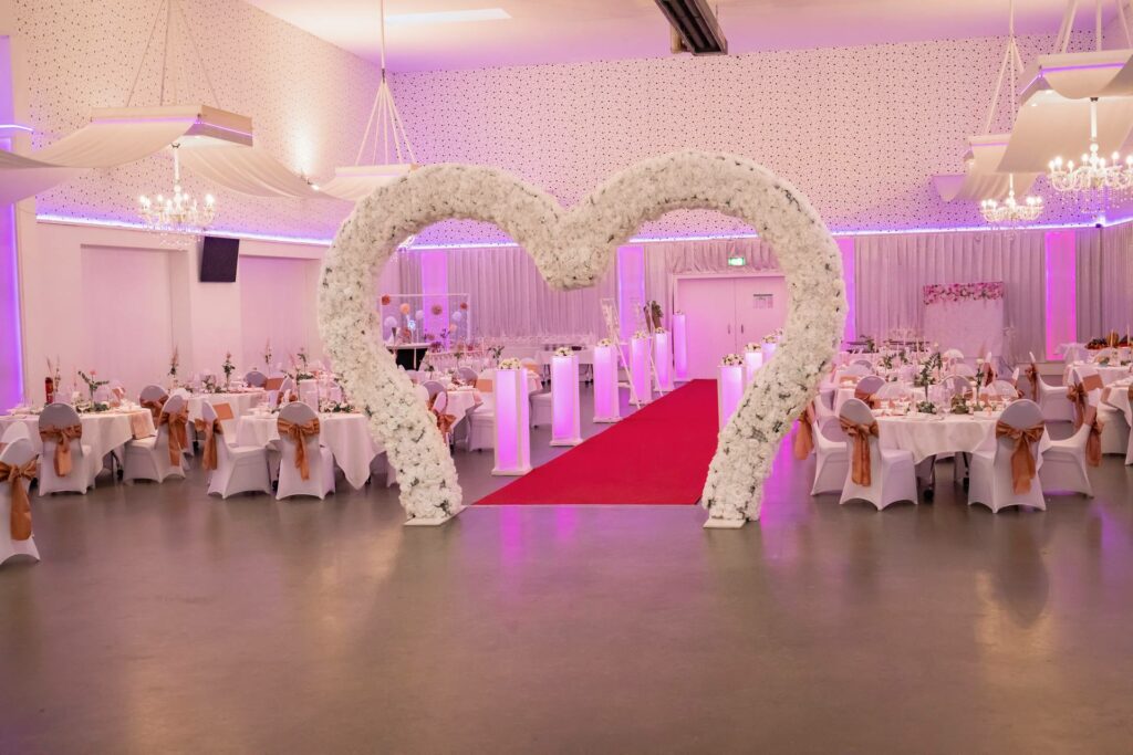 Großer Hochzeitssaal mit Blumenherz und rotem Teppich – Metadrom Eventcenter Großefehn