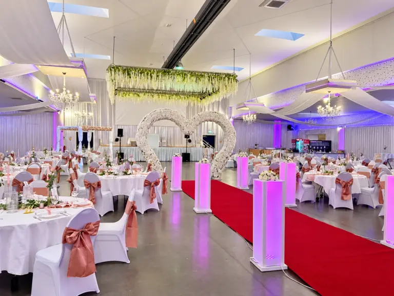 Hochzeitsgang mit Blumenherzen und rosa Stuhlschleifen – Metadrom Eventcenter Großefehn