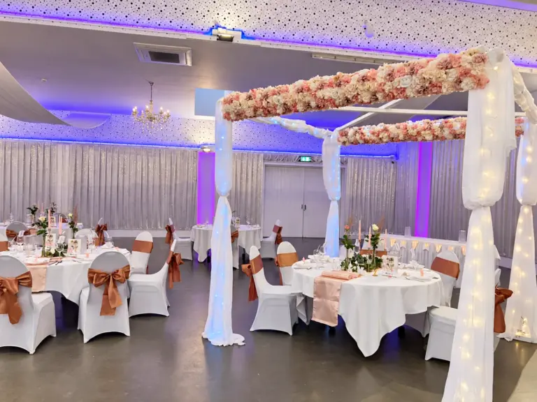 Blumenpavillon mit Lichterketten, Tische mit rosa Schleifen – Metadrom Eventcenter Großefehn