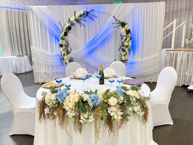 Brauttisch mit Blumenkranz und blau beleuchtetem Tuch – Metadrom Eventcenter Großefehn