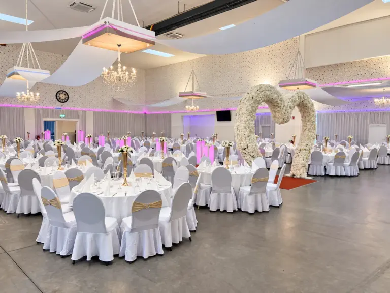 Blumenherz und Tische mit goldenen Schleifen – Metadrom Eventcenter Großefehn